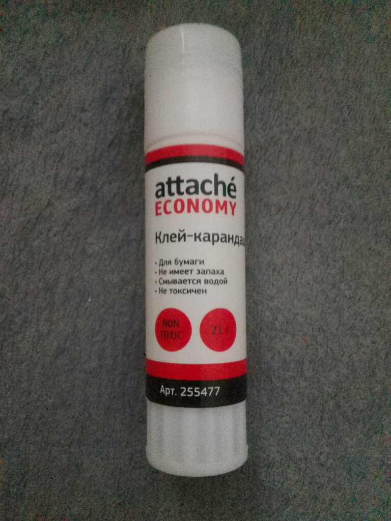 Capped Attaché Economy glue stick with a white tube and red-and-black label on a gray surface.